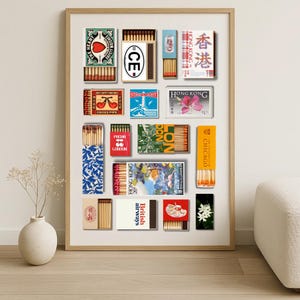 May include: A framed print featuring a collection of vintage matchboxes. The matchboxes display various designs, including text and graphics. Some boxes have text like "HONG KONG", "CHICAGO", and "British airways". The color palette includes red, blue, and yellow.