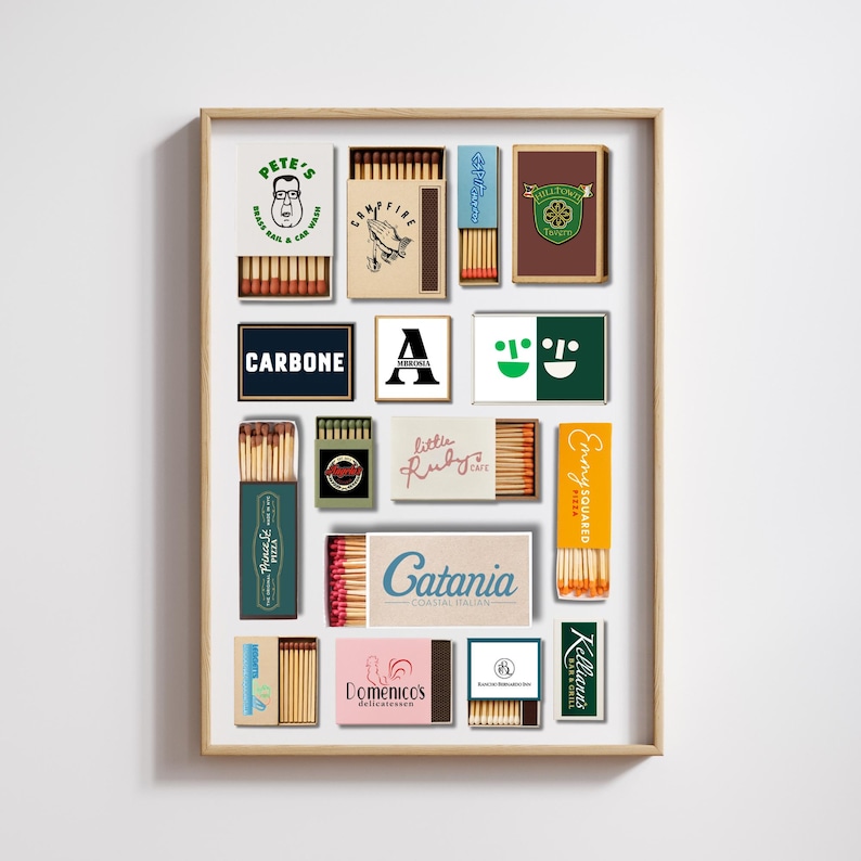 May include: A framed print featuring various vintage matchboxes. The matchboxes display logos and text, including "PETE'S," "CARBONE," "Prince St PIZZA," "little Ruby Cafe," "Catania COASTAL ITALIAN," "Domenico's delicatessen," "Emmy SQUARED," and "Kelliann's BAR & GRILL."