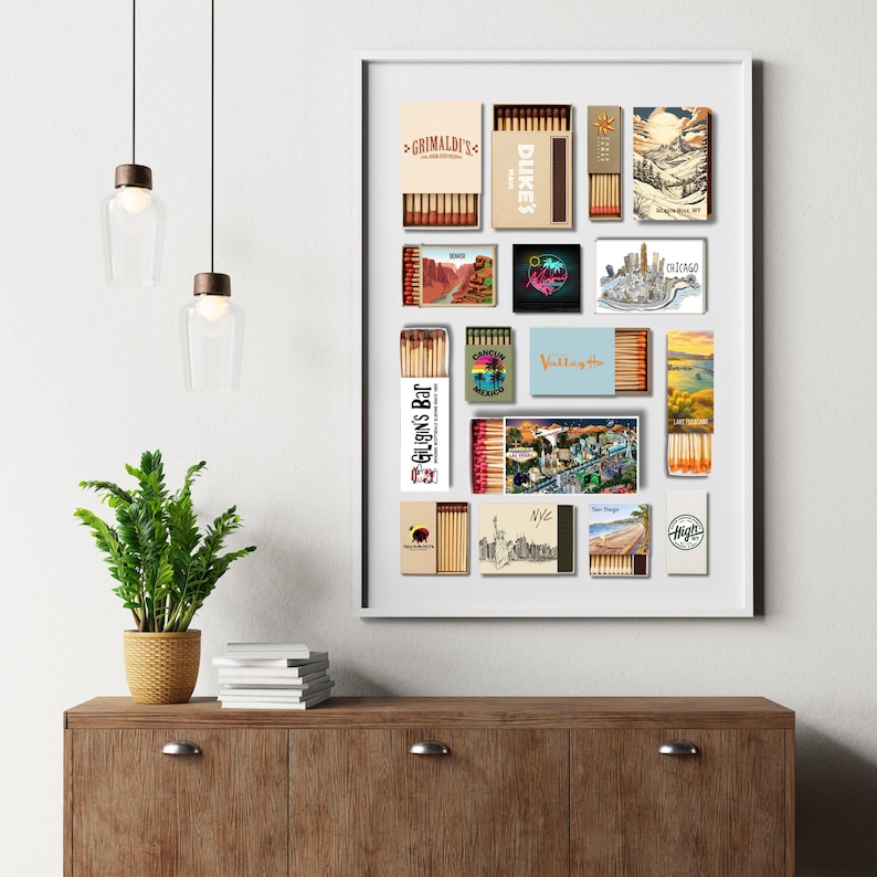 May include: A framed collection of matchboxes with various designs. The matchboxes feature images of landscapes, cityscapes, and text, including "Grimaldi's," "Dukes," and "Chicago." The arrangement is displayed on a white background.