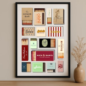 May include: A framed collection of matchboxes with various designs and text, including "the HONOR BAR", "oishii", "Even COAST", "Georgie", "Javier's", "CasaBrasa", "Las Palmas", "GREEN POINT", "NICK & SAM'S", "MUCHACHO", "Sadalle's", and "KATY".