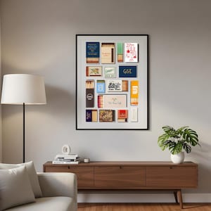 May include: A framed collection of vintage matchboxes, featuring various designs and text. The matchboxes are arranged in a grid, showcasing a range of colors and graphics. The frame is black, and the artwork is displayed on a neutral wall.