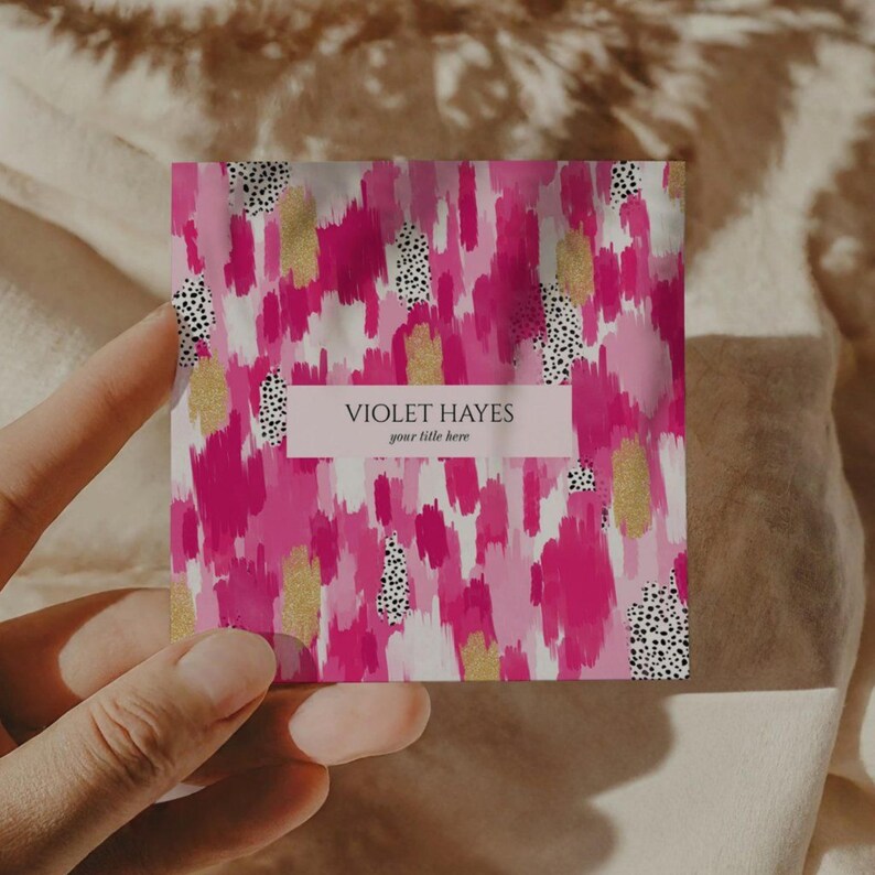 May include: A square business card with a vibrant abstract design. The background features brushstrokes of pink and magenta, accented with gold flecks and black polka dots. The card includes the text "VIOLET HAYES" and "your title here".