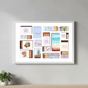 May include: A framed artwork featuring a collection of illustrated matchboxes. The designs include a horseshoe, bows, a hammock, flowers, a wine bottle, an American flag, and beach scenes. The artwork is displayed on a white wall.