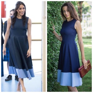 May include: A navy blue dress with a light blue hemline. The dress has a sleeveless design and a fitted bodice. The dress is knee-length and has a flared skirt.