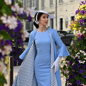 May include: A powder blue dress and long coat with bell sleeves. The coat's lining has a black and white polka dot design. The outfit is completed with a white hat, gloves, and earrings. The text "heart by closet" and "Kelly dress coat" is visible.
