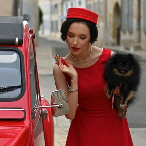 May include: A red dress with a matching hat and a small black dog. The dress is a solid color and has a simple design. The car is red and has a vintage style. The text "heartmycloset Jessica dress" is visible.