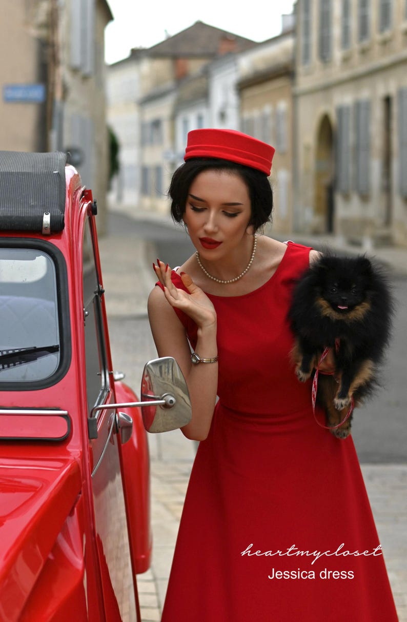 May include: A red dress with a matching hat and a small black dog. The dress is a solid color and has a simple design. The car is red and has a vintage style. The text "heartmycloset Jessica dress" is visible.