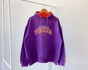 May include: Purple hooded sweatshirt with the words "Clemson Tigers" in orange embroidered on the front.
