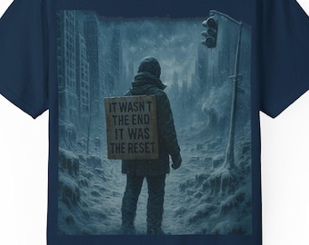 Könnte beinhalten: Ein marineblaues T-Shirt mit einem Motiv, das eine Person zeigt, die durch eine schneebedeckte, postapokalyptische Stadt geht. Die Person hält ein Schild mit der Aufschrift "Es war nicht das Ende, es war der Reset."
