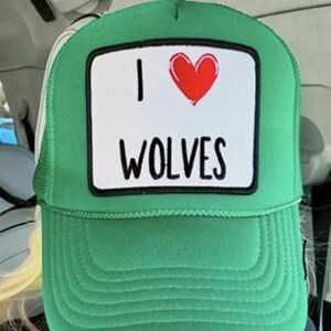May include: Green trucker hat with a white patch that says "I love wolves" and a red heart.