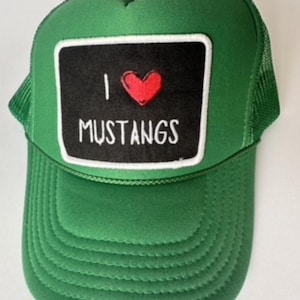 May include: Green trucker hat with a black square patch featuring a red heart and the words "I MUSTANGS" in white. The hat has a mesh back and a curved brim.
