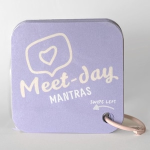 May include: A stack of lavender-colored cards with rounded corners, held together by a pink metal ring. The cards feature the text "Meet-day Mantras" and a speech bubble with a heart icon. The phrase "Swipe Left" and an arrow are also visible.