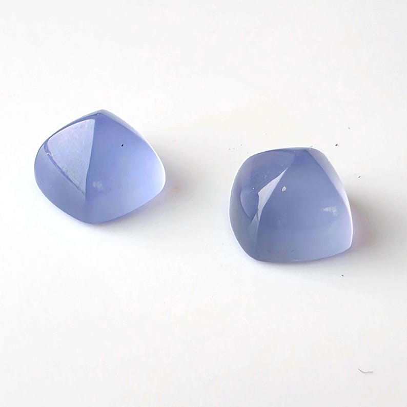 K&ouml;nnte beinhalten: Zwei polierte, hellblaue Edelsteine mit abgerundeten Kanten und einer glatten, reflektierenden Oberfl&auml;che. Die Steine sind vor einem wei&szlig;en Hintergrund platziert, der ihre Farbe und Form hervorhebt. Diese Edelsteine k&ouml;nnten f&uuml;r Schmuck oder andere Bastelarbeiten verwendet werden.