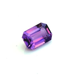 May include: A purple emerald cut gemstone with a slight pink hue.