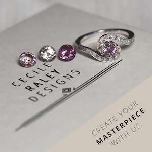 May include: A silver ring featuring a central pink gemstone surrounded by smaller pink and yellow stones, accompanied by three loose round pink gemstones. The text CECILE RALEY DESIGNS and CREATE YOUR MASTERPIECE WITH US are printed on the surface.