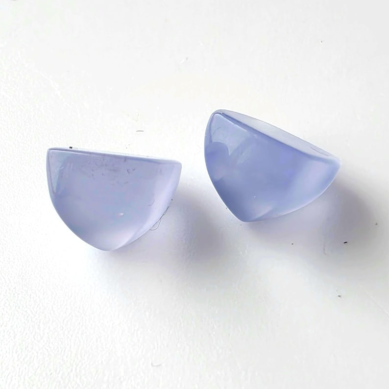 K&ouml;nnte beinhalten: Zwei halbkreisf&ouml;rmige Cabochons in hellem Periwinkle. Die polierten Steine haben eine glatte, abgerundete Oberfl&auml;che und eine flache, geschnittene Kante. Diese Cabochons sind wahrscheinlich f&uuml;r die Schmuckherstellung oder andere Bastelprojekte bestimmt.