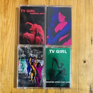 Könnte beinhalten: Vier Musikkassetten mit farbenfrohen Kunstwerken. Auf der oberen linken Kassette steht "TV GIRL FRENCH EXIT" mit einem roten und schwarzen Bild. Die obere rechte Kassette hat ein rosa und blaues Bild. Die untere linke Kassette hat ein farbenfrohes Bild von Menschen. Auf der unteren rechten Kassette steht "TV GIRL GRAPES UPON THE VINE".