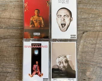 May include: Four Mac Miller music cassette tapes in clear plastic cases. The top left features a red background with a shirtless man. The top right is white with a black and white face illustration. The bottom left is white with a man in a pink suit. The bottom right is a beige portrait.
