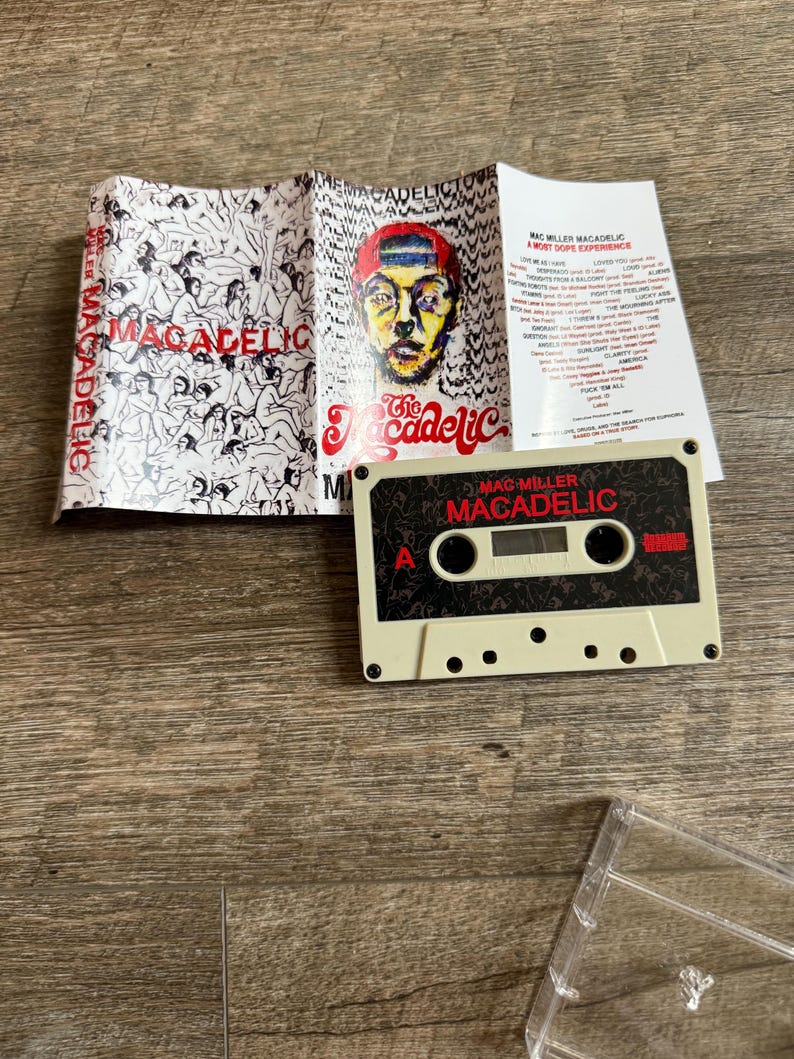 May include: A Mac Miller Macadelic cassette tape with a beige shell and black label featuring red text. The accompanying J-card insert displays a colorful portrait of a person in a red cap, a black and white illustration of figures, and a tracklist.