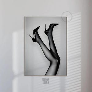 Könnte beinhalten: Schwarz-Weiß-Druck mit einem Paar Beine in schwarzen Strümpfen und High Heels. Die Stiletto-Absätze sind glänzend und spitz. Das Bild ist ein digitaler Download.