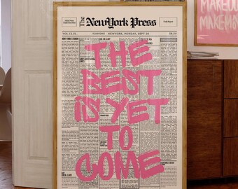 May include: A framed vertical wall art print featuring a vintage newspaper layout titled The NewYork Press. The design displays the bold pink text THE BEST IS YET TO COME overlaid on columns of black and white printed news articles and text.