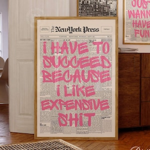 Peut inclure: Une affiche murale verticale encadrée présentant une mise en page de journal vintage intitulée The NewYork Press. L'impression affiche un texte en gras rose vif de style graffiti superposé aux colonnes : I HAVE TO SUCCEED BECAUSE I LIKE EXPENSIVE SHIT.