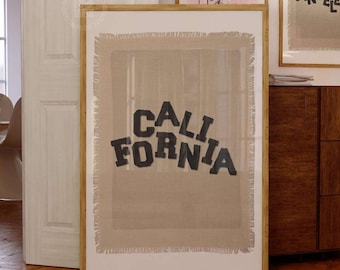May include: A framed wall art print featuring a beige, textured fabric background with frayed edges. The word CALIFORNIA is printed in bold, black, block-style letters across the center. The print is enclosed in a simple, light-colored wooden frame.
