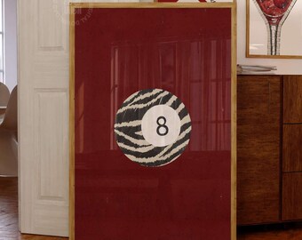 May include: A rectangular wall art print featuring a deep red background with a central circular graphic of a billiard ball numbered eight, decorated with a black and white zebra stripe pattern. The print is encased in a light-colored wooden frame.