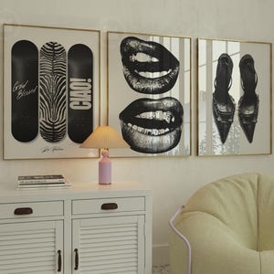 May include: Three framed wall art pieces. One features skateboards with text and a zebra print. Another shows two sets of lips in black and white. The third displays two pairs of high heels. The frames have gold trim.