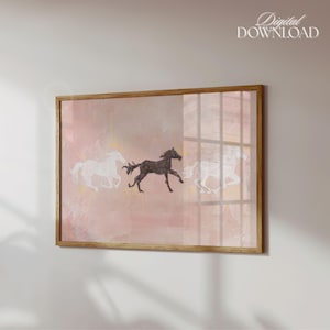 K&ouml;nnte beinhalten: Ein rechteckiger Wandkunstdruck in einem Holzrahmen mit einem weichen, rosafarbenen Aquarellhintergrund und drei Pferden in Bewegung. Zwei Pferde sind als wei&szlig;e Umrisse dargestellt, w&auml;hrend das mittlere Pferd schwarz ist. Text Digital DOWNLOAD.