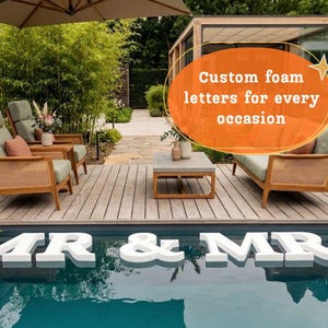Könnte beinhalten: Weiße Schaumstoffbuchstaben mit der Aufschrift "MR & MRS", die in einem Pool schwimmen. Die Buchstaben befinden sich vor einer Holzterrasse mit Gartenmöbeln. Das Bild enthält den Text "Custom foam letters for every occasion".
