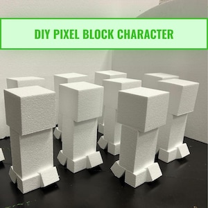 Op de afbeelding: Een verzameling witte, gepixelde blokkarakters, elk met een kubusvormig hoofd en een rechthoekig lichaam. De karakters zijn gerangschikt op een donkere ondergrond. De tekst "DIY PIXEL BLOCK CHARACTER" staat in een groene banner erboven.