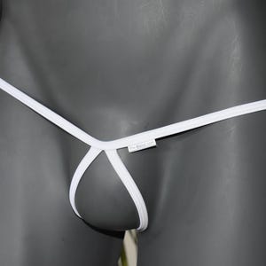 Könnte beinhalten: Weißer String-Tanga mit minimalistischem Design. Die Unterwäsche hat einen dünnen Bund und Träger mit niedrigem Bund. Der Stoff scheint ein glattes, einfarbiges Weiß zu sein. Das Kleidungsstück wird auf einer grauen Schaufensterpuppe präsentiert.