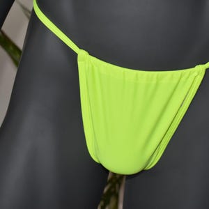 Könnte beinhalten: Limegrüne Unterwäsche mit dünnen Trägern. Die Unterwäsche ist aus einem glatten, dehnbaren Stoff.