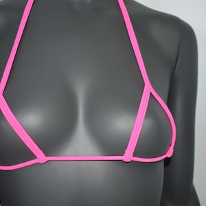 Könnte beinhalten: Ein neongelbes Bikini-Oberteil mit Neckholder-Design. Das Oberteil hat dünne Träger und einen minimalistischen Stil, der eine kräftige und lebendige Farbe zeigt. Die Bademode wird auf einer Schaufenquin ausgestellt.