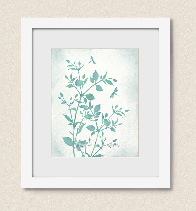 May include: A watercolor painting of a leafy branch with delicate green leaves and two dragonflies in flight against a light blue background. The painting is framed in a white frame.