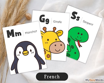 May include: Three white educational flashcards featuring black letters and colorful animal illustrations. One card shows a penguin labeled Mm Manchot, another a giraffe labeled Gg Girafe, and the third a green snake labeled Ss Serpent.