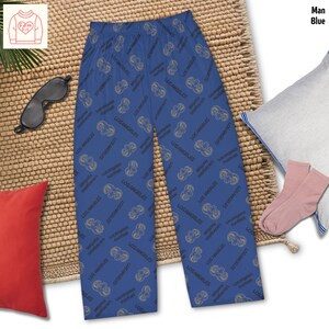 Può includere: Pantaloni da pigiama blu con un motivo ripetuto delle parole "LOS ANGELES" e una grafica di football. I pantaloni sono esposti su un tappetino intrecciato, con un cuscino rosso, una mascherina per gli occhi e calzini rosa.