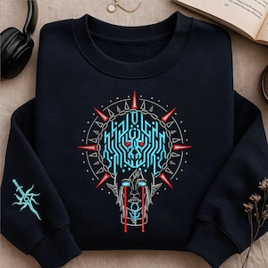 Könnte beinhalten: Ein marineblaues Sweatshirt mit detailliertem Grafikdesign. Das Design zeigt ein stilisiertes Gesicht mit roten Augen und Tränen, umgeben von einem schaltungsähnlichen Muster in Blau und Weiß. Auf dem linken Ärmel befindet sich ein schwertartiges Emblem.