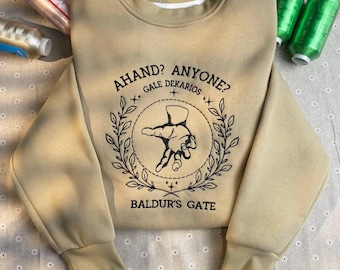 Op de afbeelding: Een beige sweatshirt met een zwarte grafische print van een hand met de tekst "A hand? Anyone? Gale Dekarios" en "Baldur's Gate".