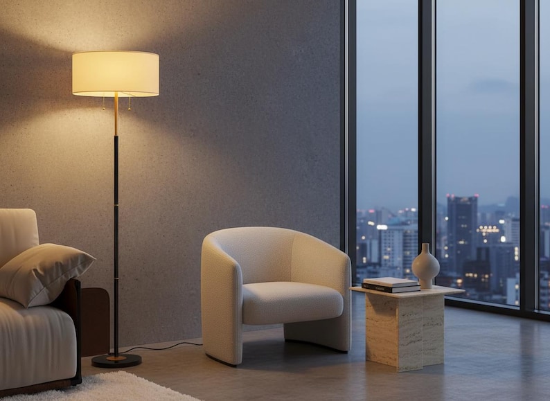 Pu&ograve; includere: Una scena di soggiorno moderno con una poltrona color crema, una lampada da terra con un paralume beige e un tavolino. La stanza ha una grande finestra con vista sulla citt&agrave; e una palette di colori neutri.