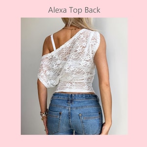 May include: White lace one-shoulder top with a floral pattern. The top is paired with blue denim jeans. The text "Alexa Top Back" is visible at the top of the image.