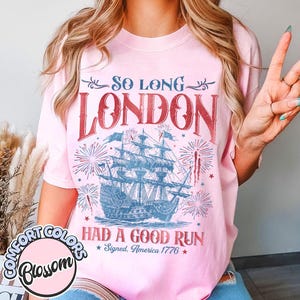 May include: A light pink t-shirt with the text "SO LONG LONDON HAD A GOOD RUN Signed, America 1776" in red and blue. The design includes a ship and fireworks.