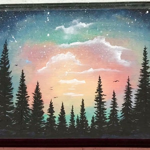 May include: A painting of a forest silhouette against a colorful sunset sky. The sky is painted in shades of pink, orange, yellow, green, and blue, with white clouds. The trees are black and are arranged in a row across the bottom of the painting.
