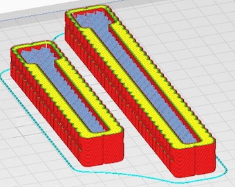 May include: Two red and yellow 3D printed objects with a blue interior. The objects are shaped like long, thin rectangles with a rounded top and bottom.