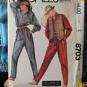 May include: A McCall's sewing pattern for a jumpsuit with two different styles. The first style is a blue denim jumpsuit with a button-up shirt and a belt. The second style is a red jumpsuit with a plaid vest and a hat. The pattern number is 8703 and the size is small.