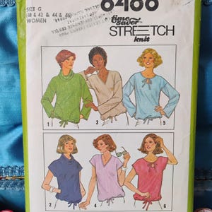May include: A vintage Simplicity sewing pattern envelope, featuring illustrations of women's tops. The pattern number is 8488, with the words "Stretch Knit" prominently displayed. The envelope is green and white, with text and illustrations.
