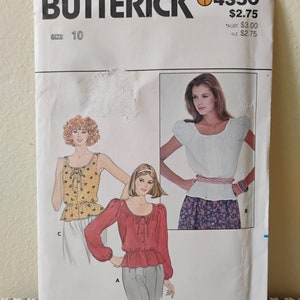 May include: A vintage sewing pattern for a blouse with three different styles. The pattern is from Butterick and is size 10. The pattern shows three different styles of blouses, one with a ruffled neckline, one with a scoop neckline, and one with a square neckline.