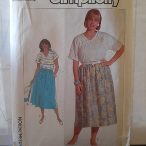 May include: Simplicity sewing pattern featuring two women's outfits. One outfit includes a V-neck top and floral skirt, the other a striped top and solid skirt. The pattern size is W (20+22+24).
