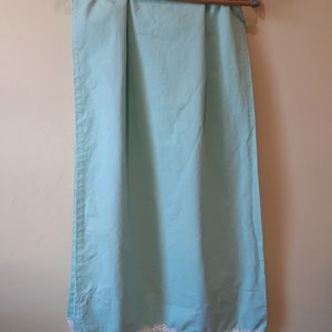 May include: A light blue curtain with a white crocheted lace trim.